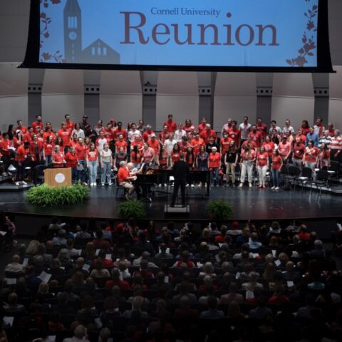 Large group choir in front of a slide that says reunion