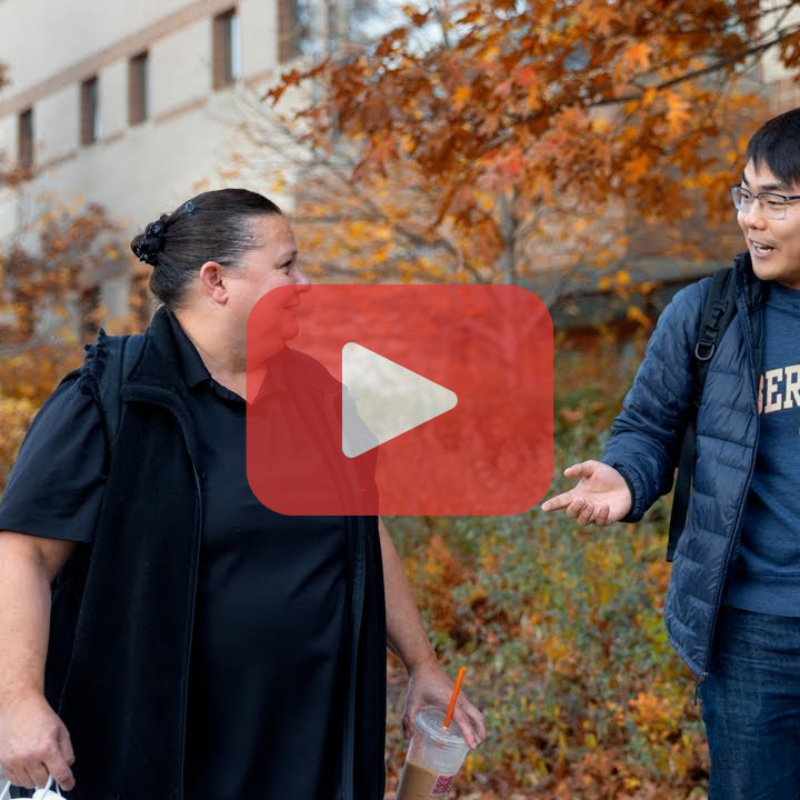 student and advisor walking and talking with a play button overlaid